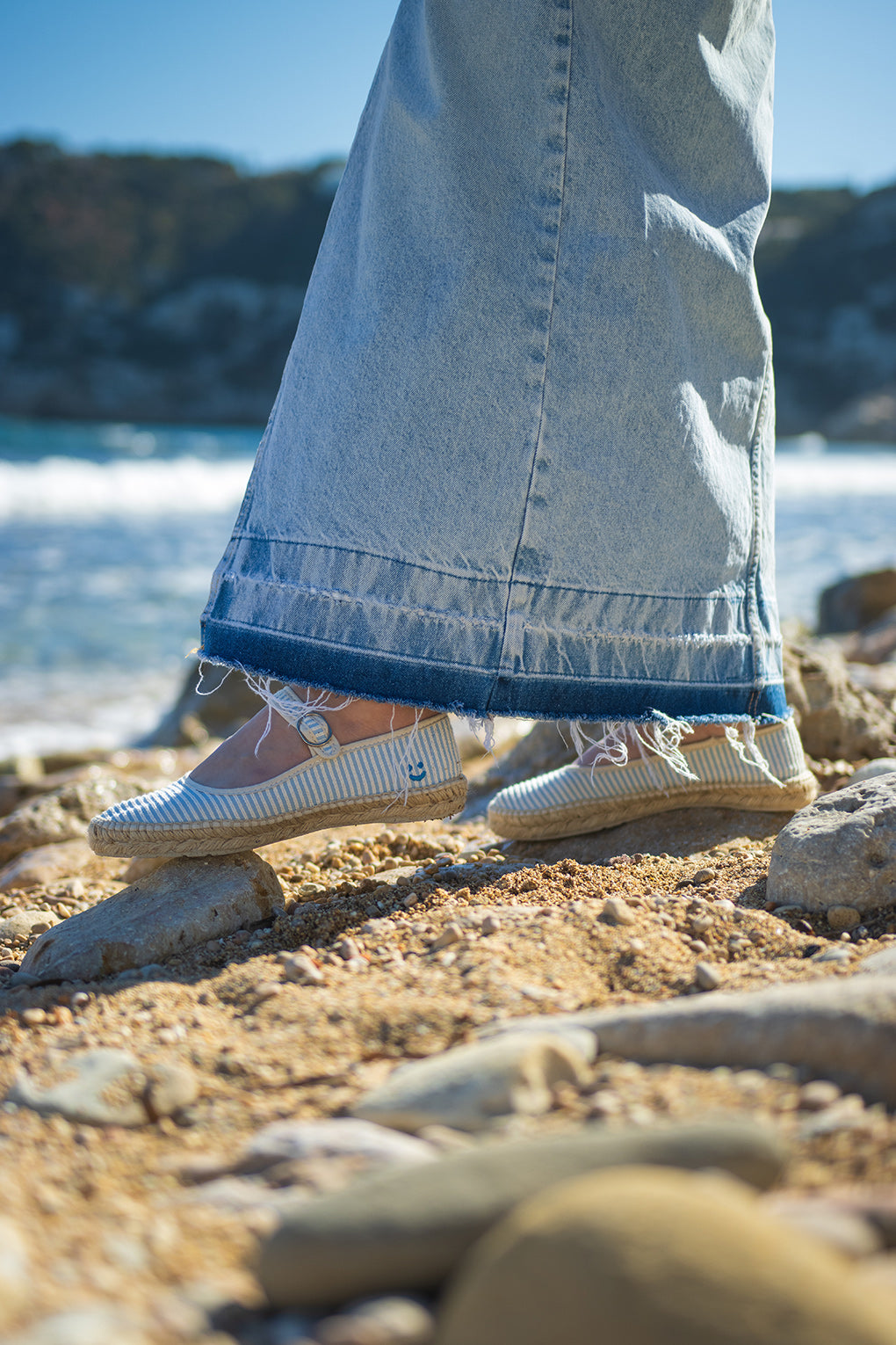 Detalle bailarina a rayas azules con suela de yute natural frente al mar. Las alpargatas Valetta Cielo son perfectas para el verano. Hechas en España a mano con materiales sostenibles y aroma a cítricos. 