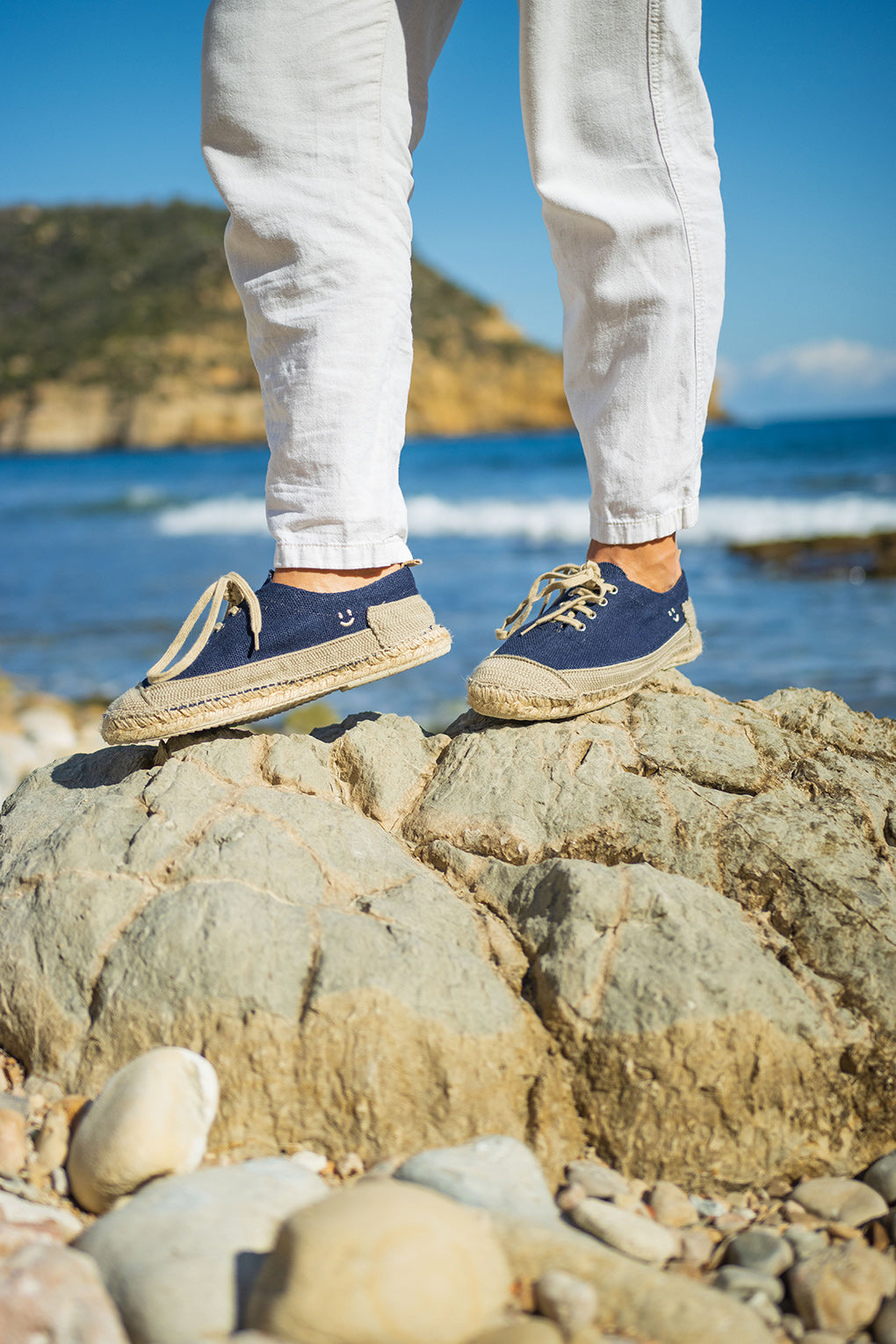 Detalle sobre roca frente al mar de las alpargatas Peñíscola Azul de MYBARKS. Calzado con esencia mediterránea cosido a mano en España con materiales sostenibles. Alpargatas diferentes para hombre. 