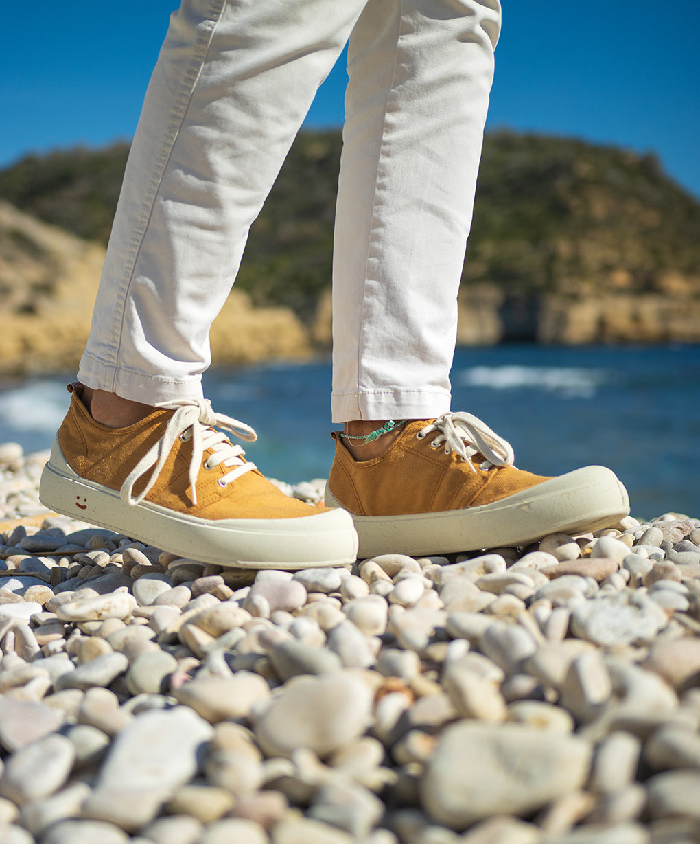 Detalle de las zapatillas para hombre Menorca Caña. Zapatillas en color amarillo mostaza hechas en España con materiales sostenibles y aroma a bosque mediterráneo. Algodón orgánico, caucho natural y corcho reciclado. 